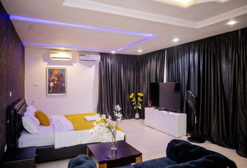 a bedroom with a bed and a tv and curtains at LEKKI SECRET MANSION 'n' SWIMMING POOl in Aja