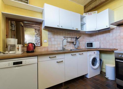 a kitchen with white cabinets and a washing machine at Le Cavalier in Caraman