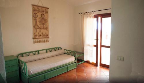 een slaapkamer met een groen bed en een raam bij Villaggio Piscina Rei in Monte Nai