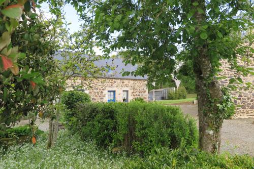 a brick house with a blue door in a yard at Les Gîtes de Douar Bouillon in La Chapelle-Neuve