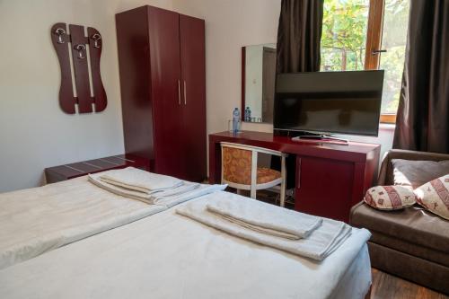 una camera d'albergo con due letti e una TV a schermo piatto di Дановатъ къща a Zgorigrad