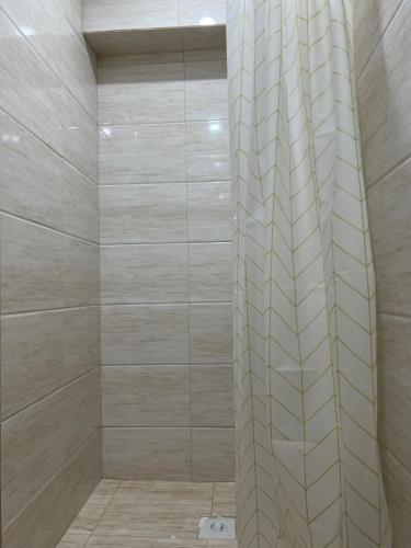 a shower with beige walls and a tile wall at Radugawest2 in Koshkolʼ