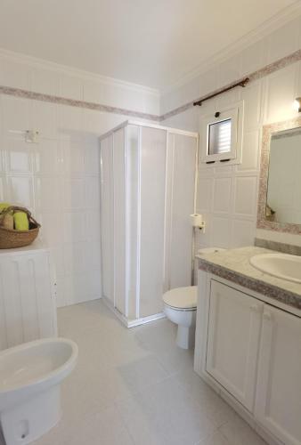 a white bathroom with a toilet and a sink at Atardecer in La Santa