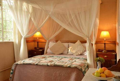 een slaapkamer met een bed met gordijnen en fruit op een tafel bij Muchenje Self Catering Cottages in Chobe