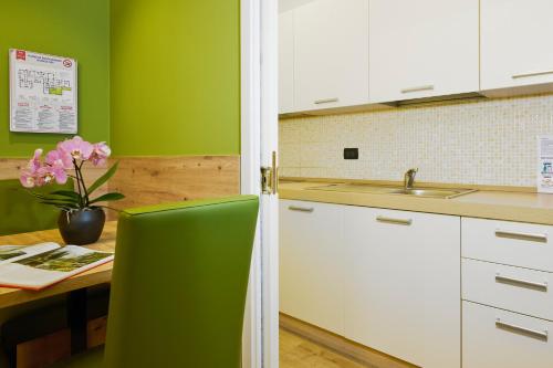 a kitchen with green walls and a table with a vase of flowers at Residence Hotel Miralago in Pergine Valsugana