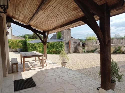 eine Terrasse mit einer hölzernen Pergola und einem Tisch in der Unterkunft Le Gîte de Bel Air in Cravant-les-Coteaux