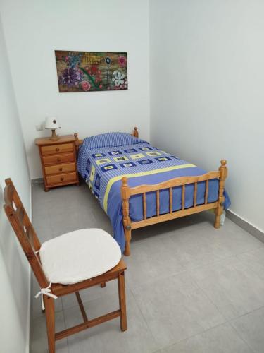 a small bedroom with a bed and a chair at Casa Magec in Arinaga