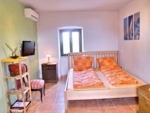 a bedroom with a bed with orange pillows and a television at Appartement Caspar- Turm Krk in Sveti Vid-Miholjice