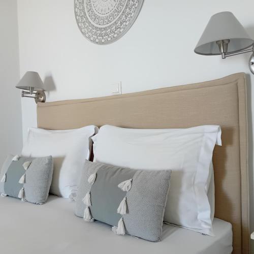 a bed with white and gray pillows and two lamps at elena in Adamas
