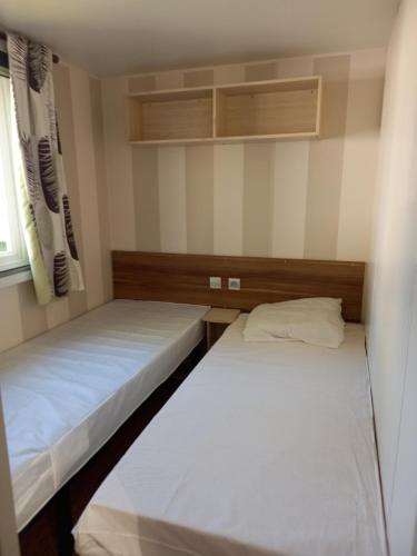 deux lits dans une petite pièce avec une fenêtre dans l'établissement mon bonheur, à Jullouville