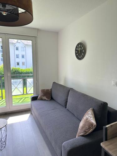un salon avec un canapé et une horloge au mur dans l'établissement Charmant Studio Le Bourget-du-Lac, au Bourget-du-Lac