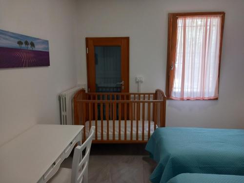 een slaapkamer met een kinderbedje en een raam en een kinderbedje bij casa vacanze cedro in San Lazzaro di Savena