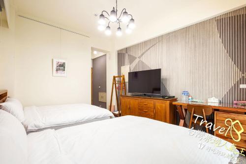 a bedroom with two beds and a desk with a tv at 不晚文旅 in Taitung City