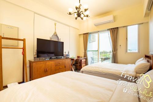 a bedroom with two beds and a flat screen tv at 不晚文旅 in Taitung City