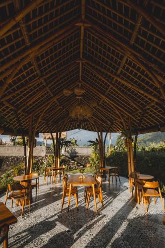a group of tables and chairs under a large umbrella at Nivriti Bali in Sidemen
