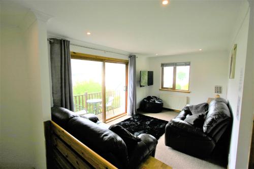 een woonkamer met 2 leren banken en een balkon bij Loch View Holiday Home, Fort William in Fort William