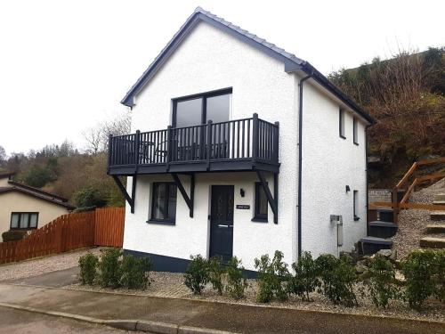 een wit huis met een balkon erbovenop bij Loch View Holiday Home, Fort William in Fort William