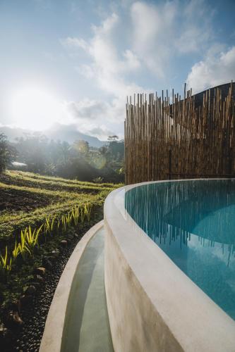 a swimming pool in the middle of a field at Nivriti Bali in Sidemen