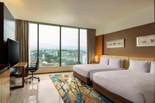 a hotel room with two beds and a large window at Hilton Bandung in Bandung
