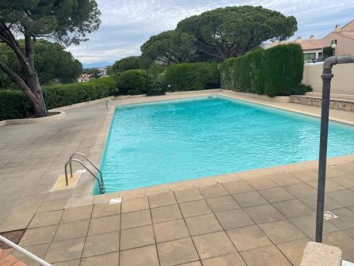 une piscine avec de l'eau bleue dans une cour dans l'établissement Apt Rez de jardin piscine dans résidence, à Fréjus