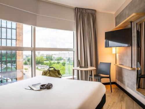 a hotel room with a bed and a large window at ibis budget Paris Porte de Montreuil in Montreuil