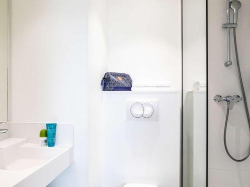 a white bathroom with a shower and a toilet at ibis budget Paris Porte de Montreuil in Montreuil
