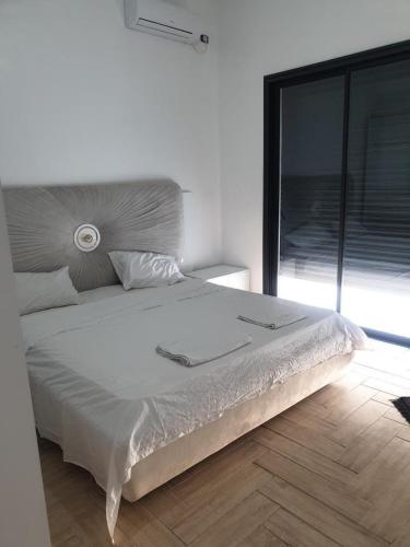 a white bed in a bedroom with a large window at Très belle villa avec piscine in Midoun