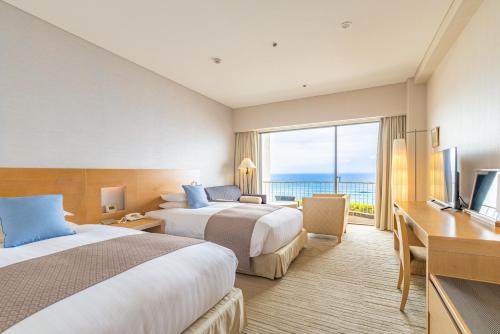 a hotel room with two beds and a television at Izu Imaihama Tokyu Hotel in Kawazu