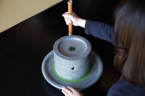 a woman holding a mortar and pestle in a bowl at 池の山荘 in Yame