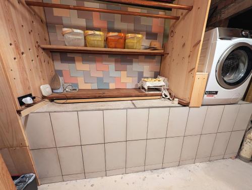 a kitchen with a washing machine and a tiled wall at AranEtxea in Bigues i Riells