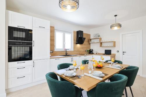 a kitchen with a wooden table and green chairs at CROWONDER Villa Bura with Heated Swimming Pool and Jacuzzi in Privlaka