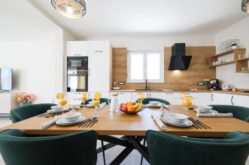 a kitchen with a wooden table and green chairs at CROWONDER Villa Bura with Heated Swimming Pool and Jacuzzi in Privlaka