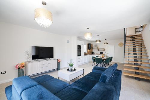 a living room with a blue couch and a kitchen at CROWONDER Villa Bura with Heated Swimming Pool and Jacuzzi in Privlaka