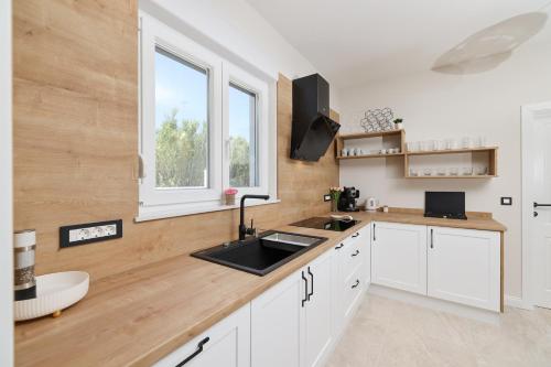 a kitchen with white cabinets and a sink and a window at CROWONDER Villa Bura with Heated Swimming Pool and Jacuzzi in Privlaka