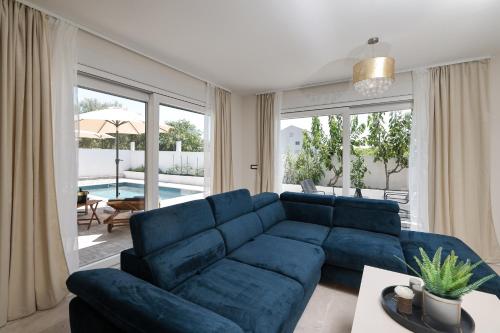 a blue couch in a living room with a large window at CROWONDER Villa Bura with Heated Swimming Pool and Jacuzzi in Privlaka