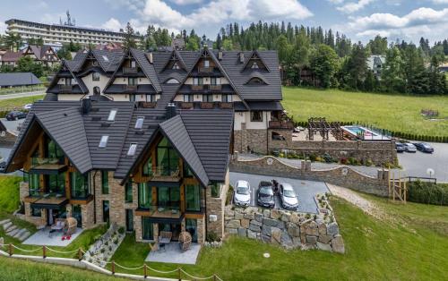 a large house with cars parked in front of it at Pensjonat Orlik Mountain Resort&SPA in Bukowina Tatrzańska