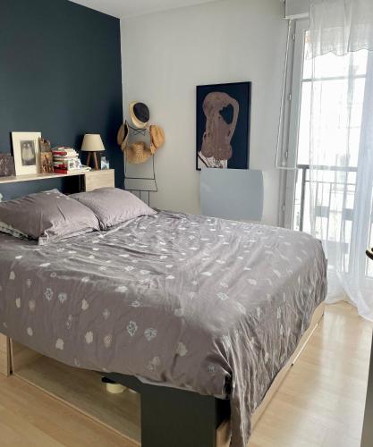 - une chambre avec un lit et une couette grise dans l'établissement Joli 2p terrasse à Saint Ouen touchant Paris, tout confort free WIFI, à Saint-Ouen
