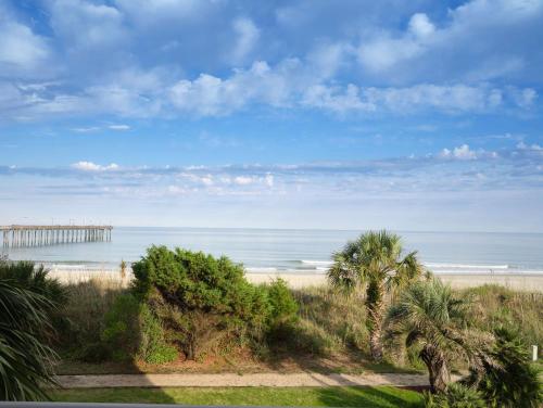 a view of the beach with a pier in the distance at The Ellie Beach Resort Myrtle Beach, Tapestry By Hilton in Myrtle Beach