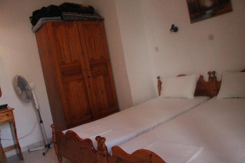 a bedroom with two beds and a wooden cabinet at ΜΑΧΗ Ενοικιαζόμενα δωμάτια in Mithymna