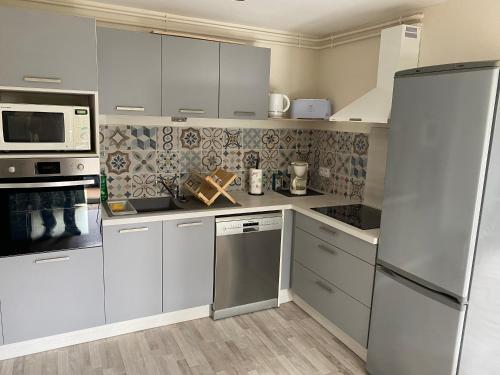 une cuisine avec des armoires blanches et des appareils en acier inoxydable dans l'établissement Appartement 2 chambres avec jardin privatif, à Châteaugay