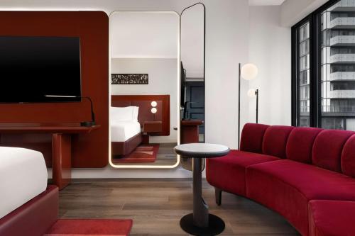 a living room with a red couch and a mirror at Revery Toronto Downtown, Curio Collection by Hilton in Toronto