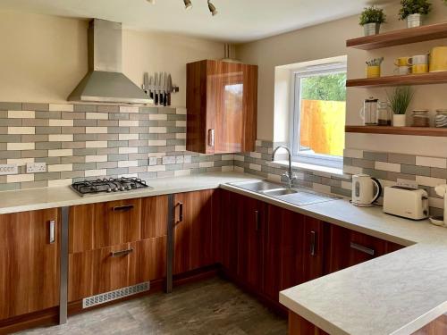 a kitchen with wooden cabinets and a sink and a window at 3 bed house near York centre with off road parking in York