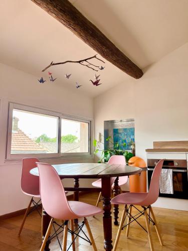 une salle à manger avec une table et des chaises roses dans l'établissement A spacious, sunny & calm loft in Avignon’s heart, à Avignon