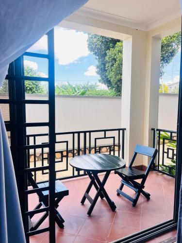 a patio with a table and chairs on a balcony at Apartment unit- Urban chills in Bulindo