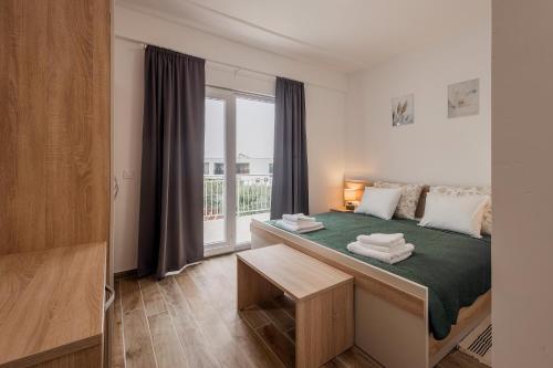 a bedroom with a bed with a green blanket and a window at Villa Milutin 1 in Vrsi