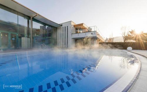 a large swimming pool with the sun in the background at Alping Apartments in Brunico