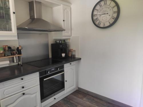 une cuisine avec des placards blancs et une horloge murale dans l'établissement Maison avec jardin à Portiragnes, à Portiragnes