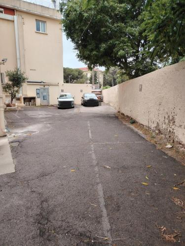 a parking lot with two cars parked next to a wall at Cit'Hotel Imperial in Sète