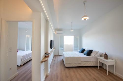 a white bedroom with a bed and a tv at Holm Corfu in Gouvia