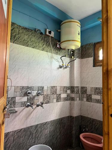 a bathroom with a toilet and a bucket on the wall at Yamuna Guest House Tosh in Tosh